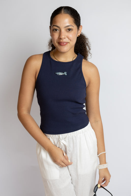 Woman wearing a navy tank top with a small graphic design on a plain background