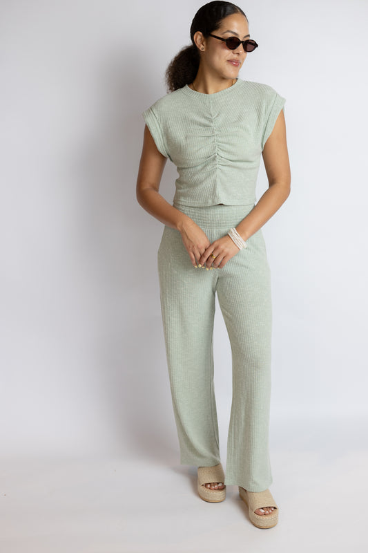 Woman wearing a light green outfit with matching pants and top on a white background