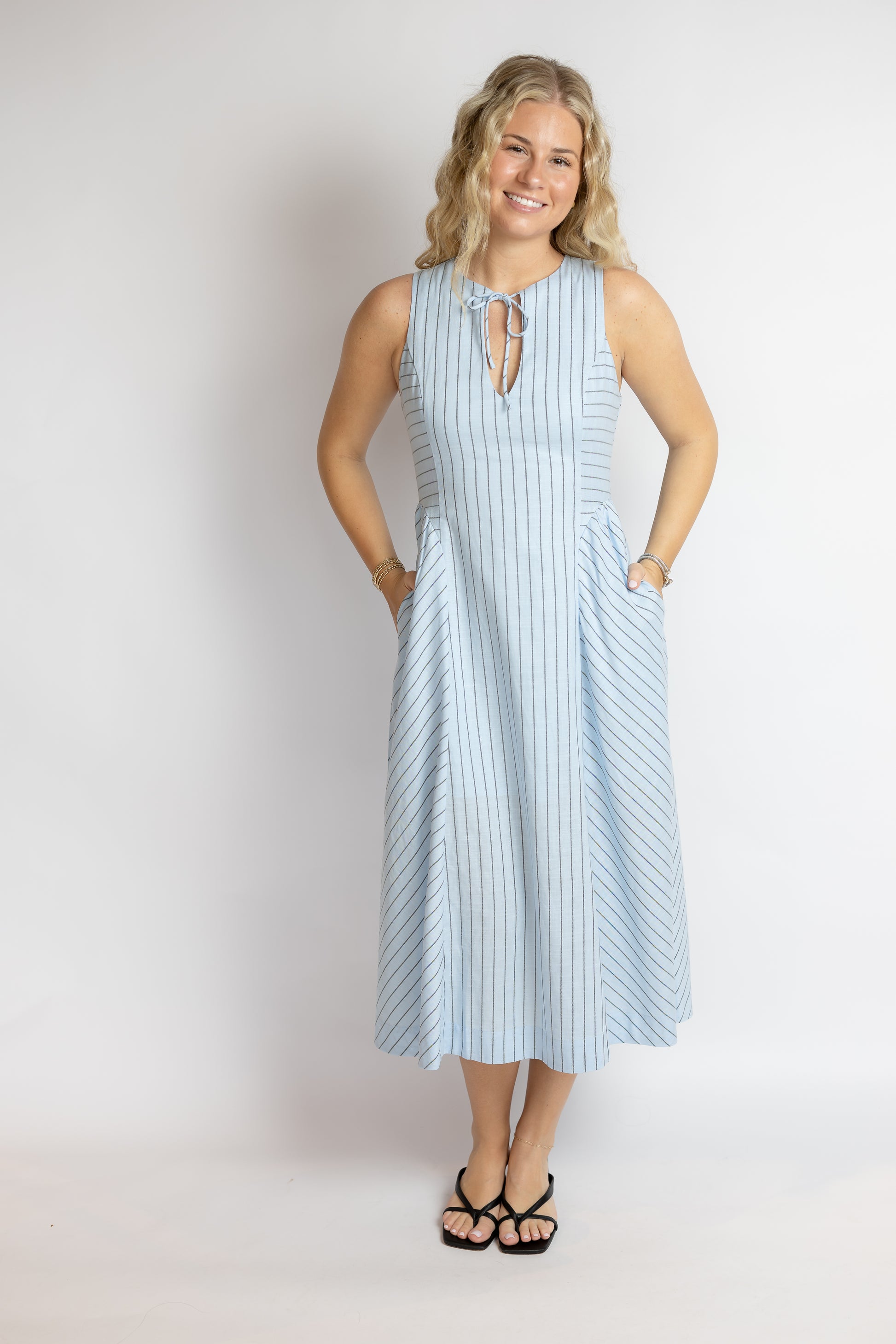 Woman wearing a light blue striped dress against a plain background