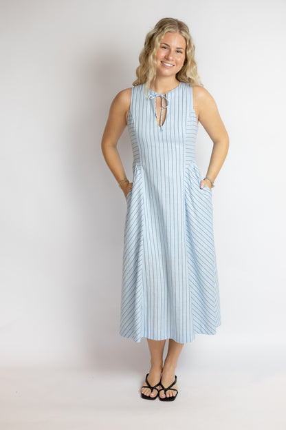 Woman wearing a light blue striped dress against a plain background