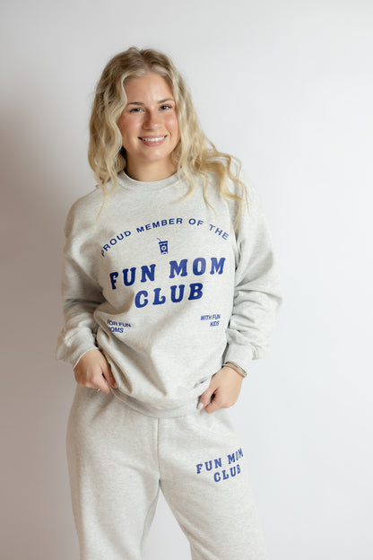 Woman wearing a 'Proud Member of the Fun Mom Club' sweatshirt and pants on a plain background