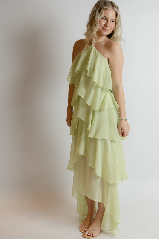 Woman wearing a light green ruffled dress against a plain background