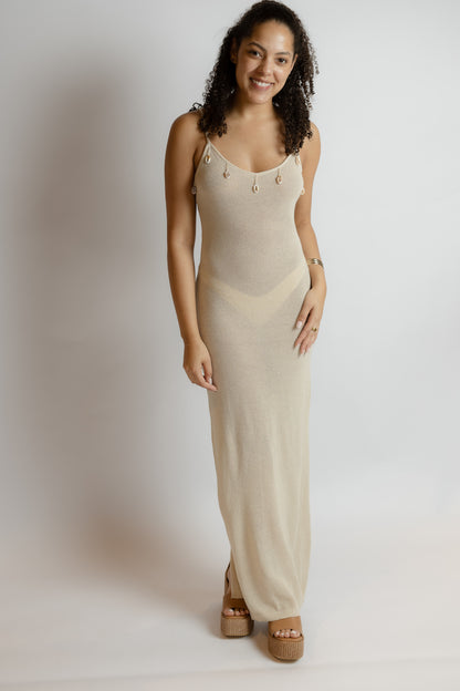 Woman wearing a beige sleeveless dress against a plain background