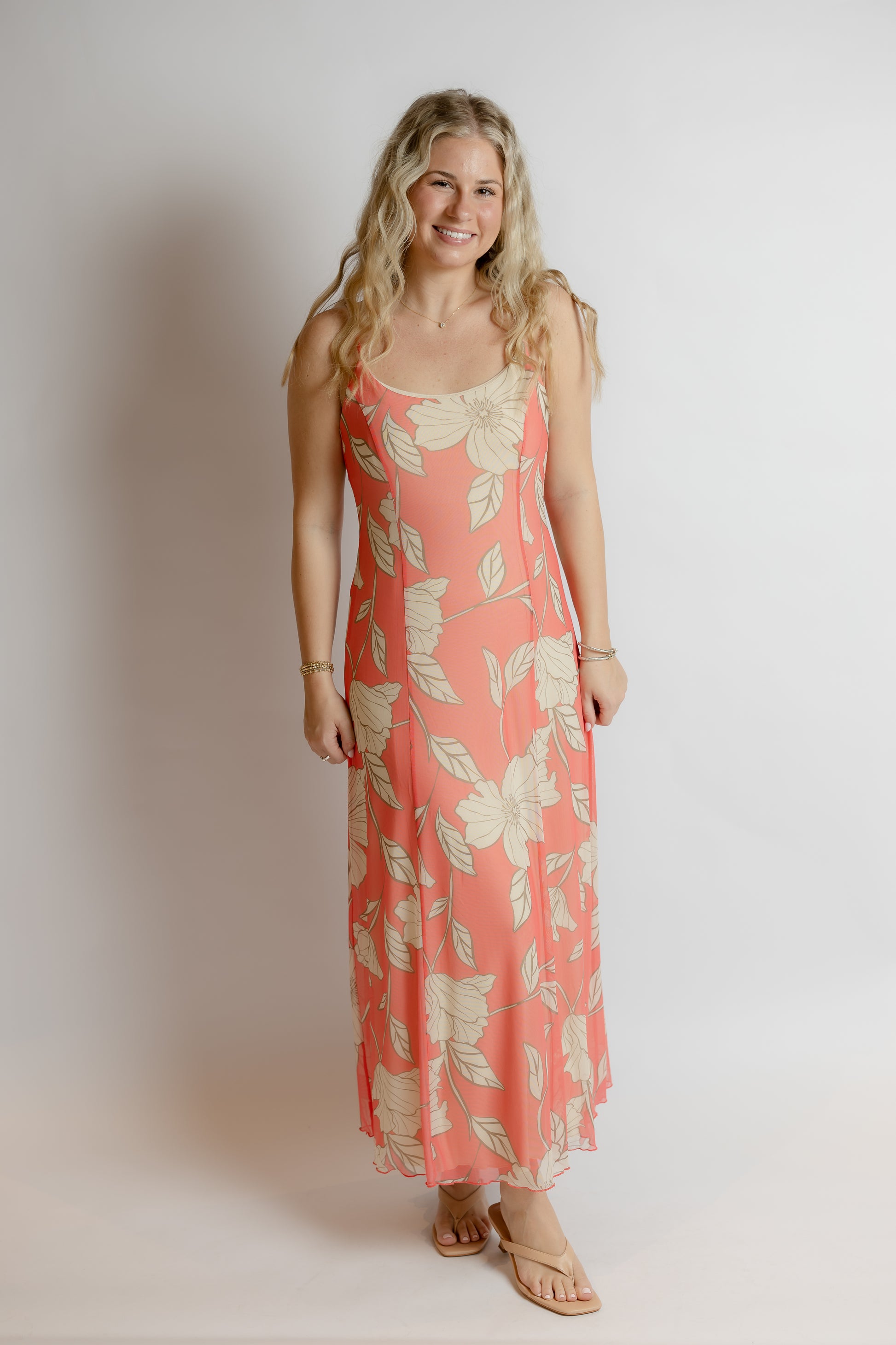 Woman wearing a coral floral dress against a plain background