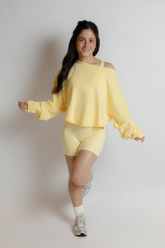 Woman wearing a yellow athletic set on a plain background