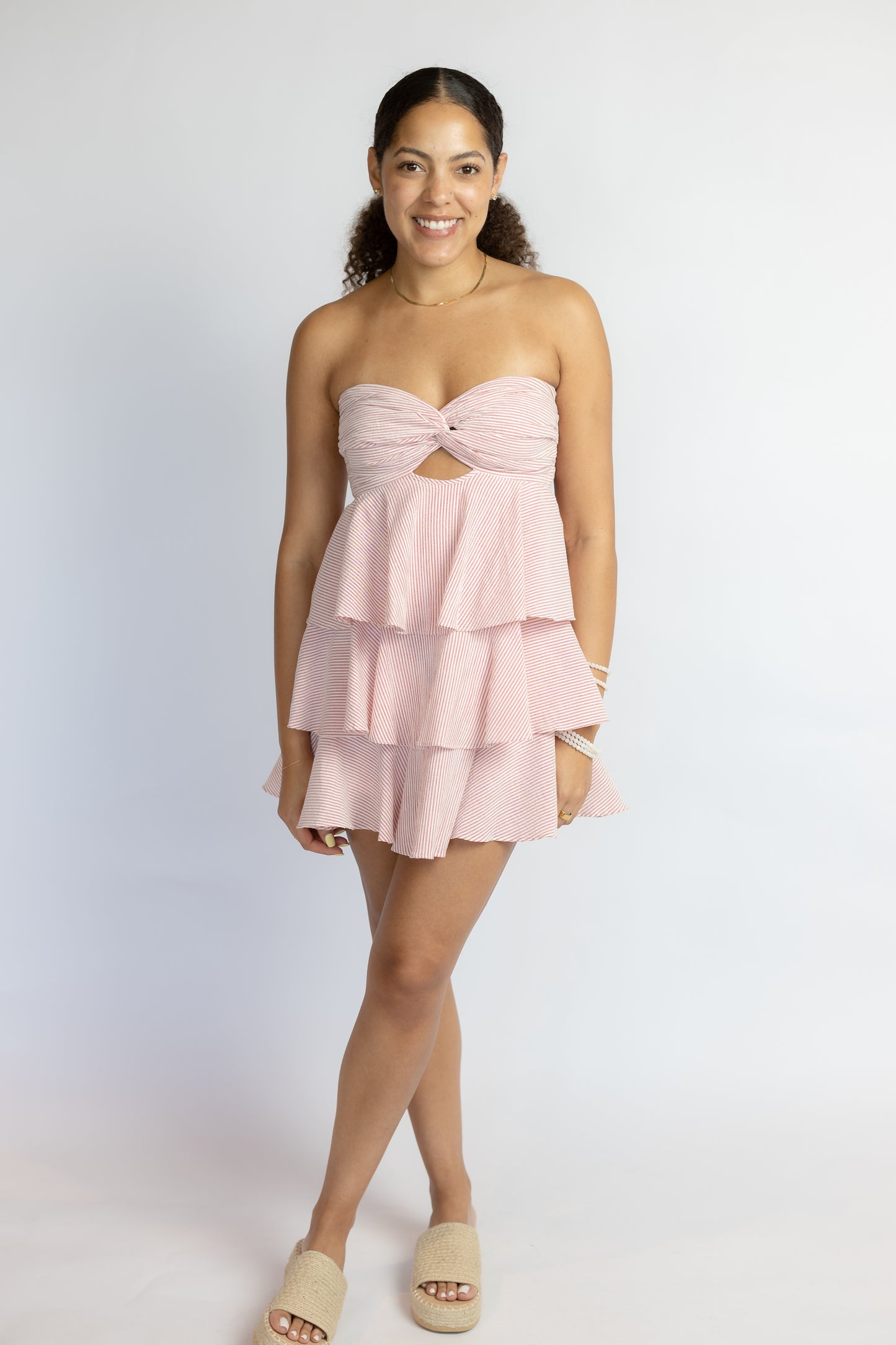 Woman wearing a pink strapless dress with ruffled layers on a white background