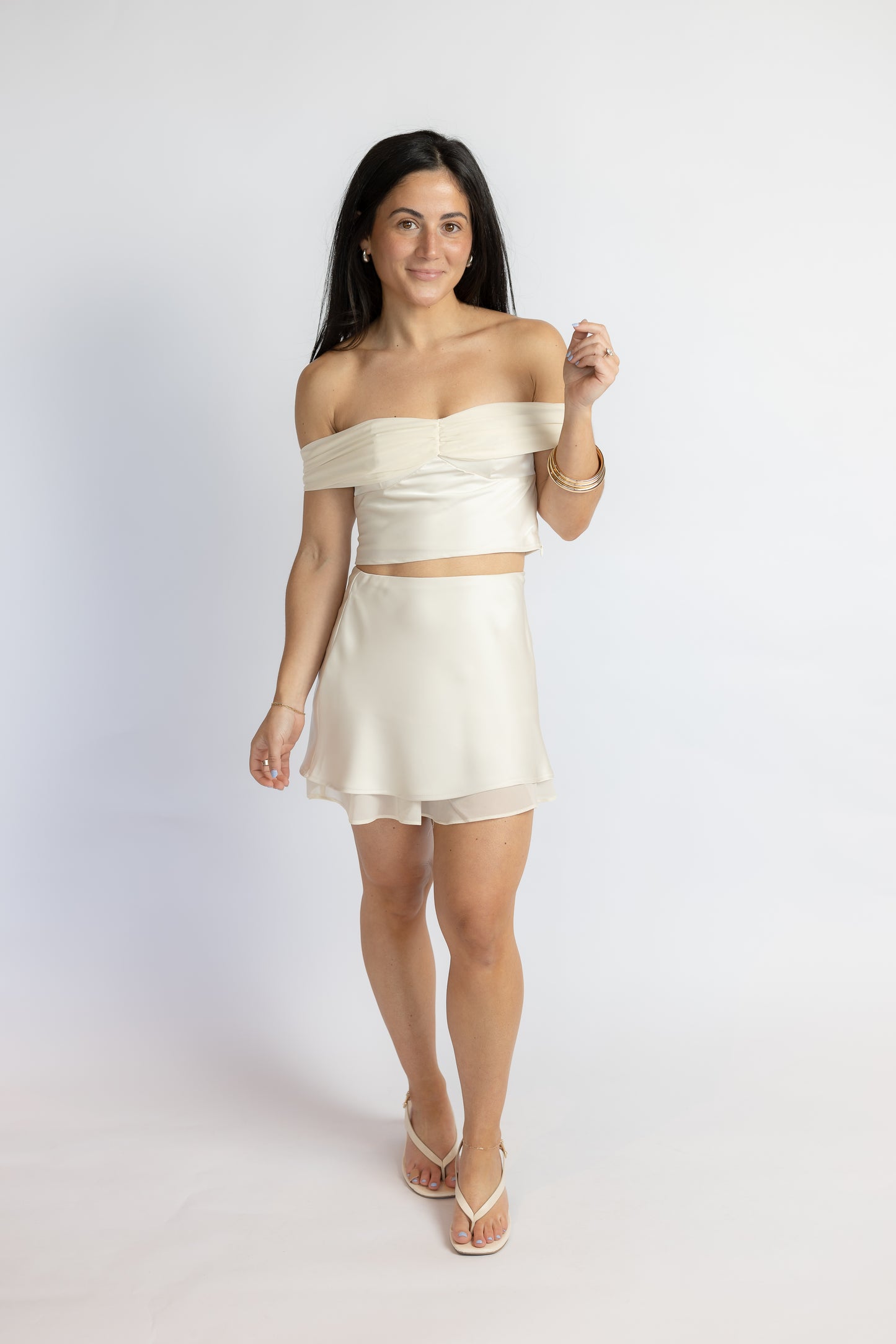Woman wearing a white strapless top and skirt set on a plain background