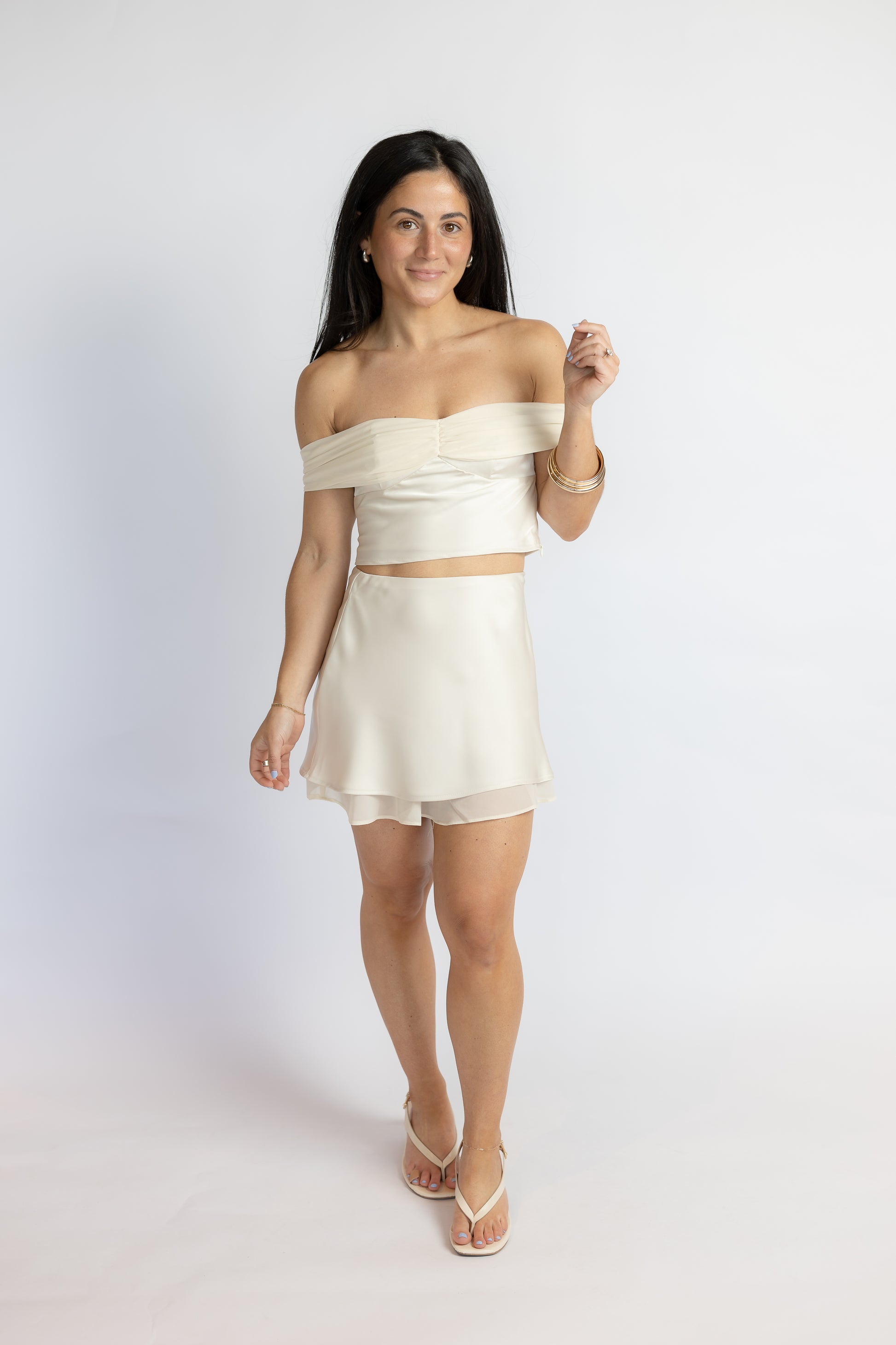Woman wearing a white strapless top and skirt set on a plain background