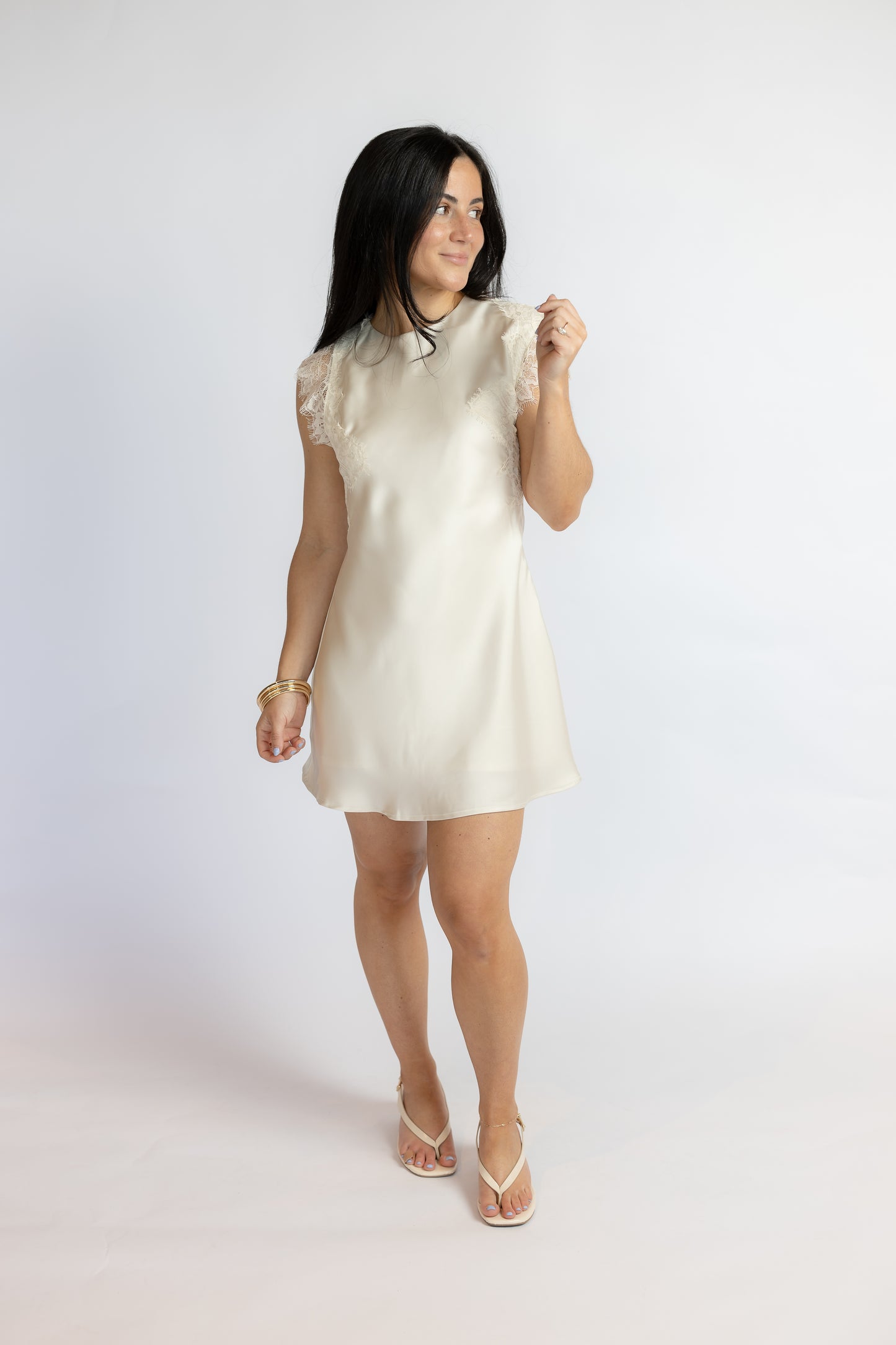 Woman wearing a white lace dress against a plain background