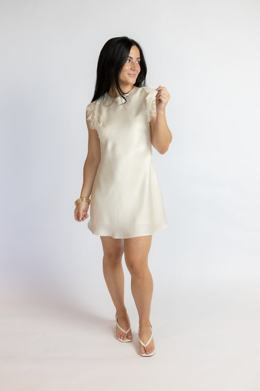 Woman wearing a white lace dress against a plain background