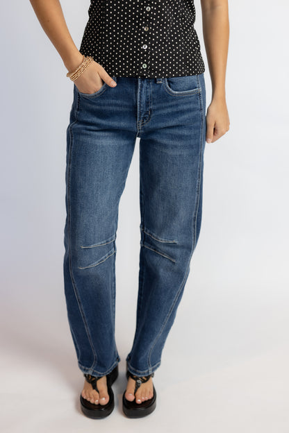 Person wearing blue jeans and a black polka dot top on a white background