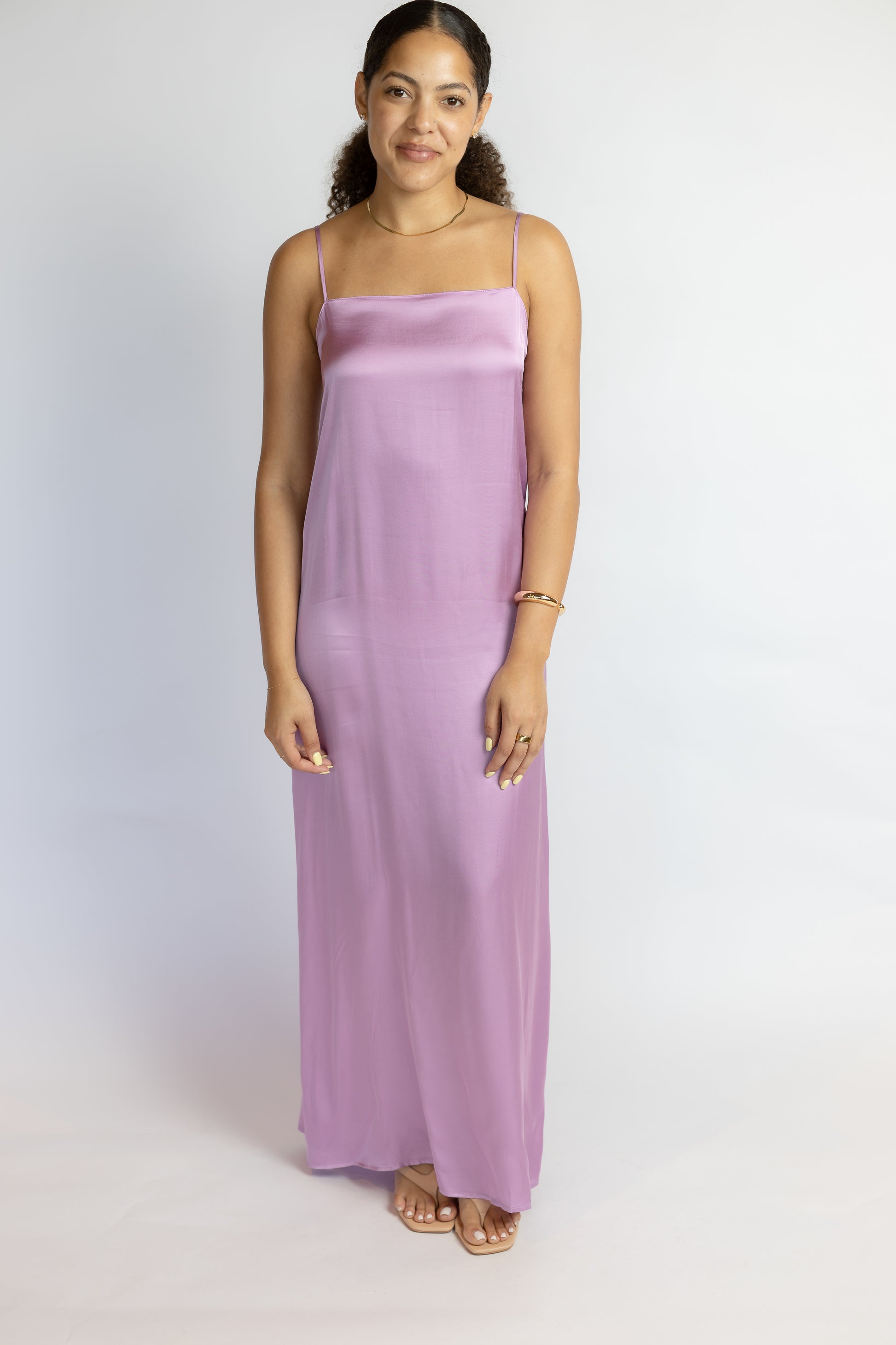 Woman wearing a long purple dress against a white background