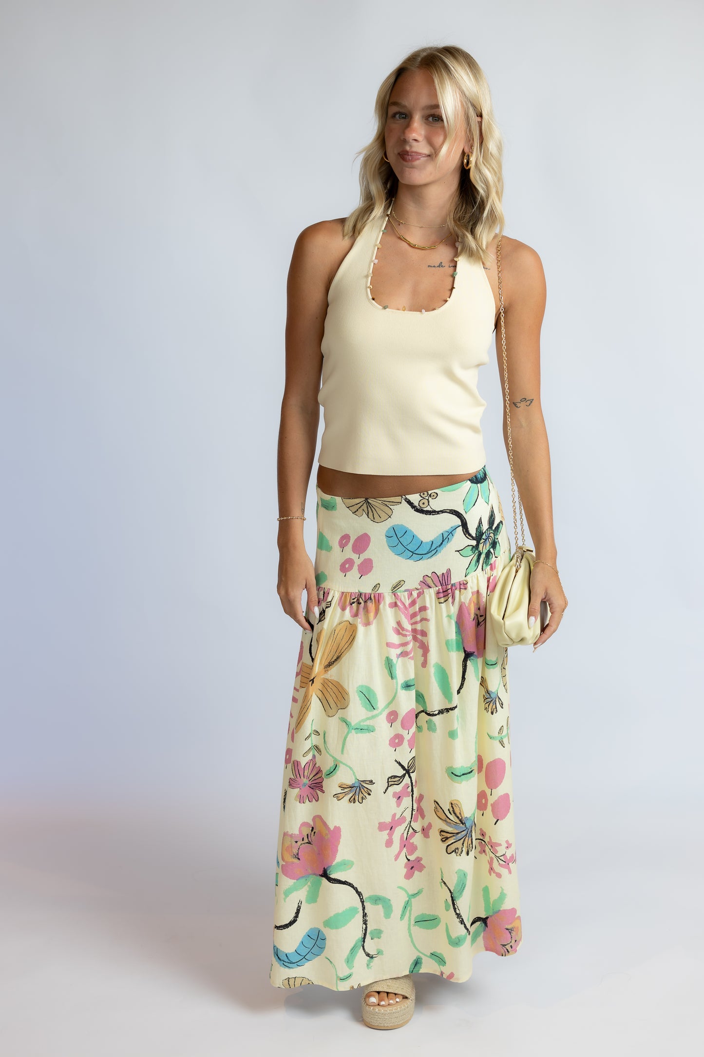 Woman wearing the Maggie butter yellow ribbed knit halter top with colorful stone trim along the neckline.