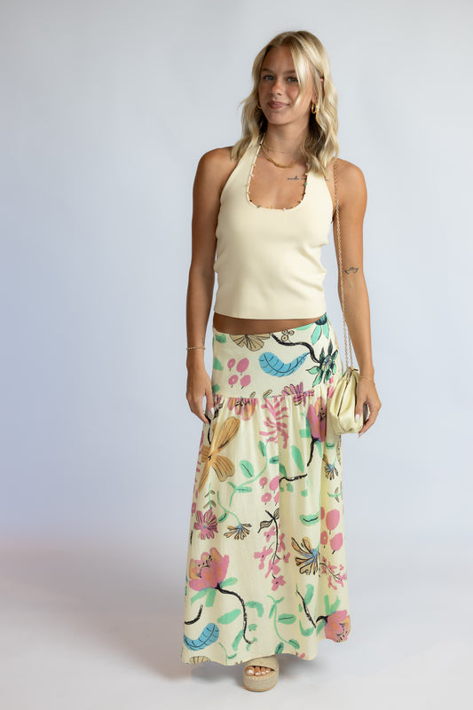 Woman wearing the Maggie butter yellow ribbed knit halter top with colorful stone trim along the neckline.