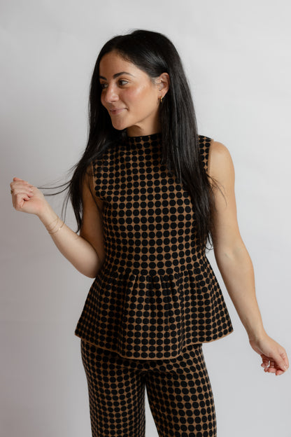 A woman modeling a sleeveless peplum top and matching pants set in a brown and black checkered pattern, set against a plain light gray studio background.