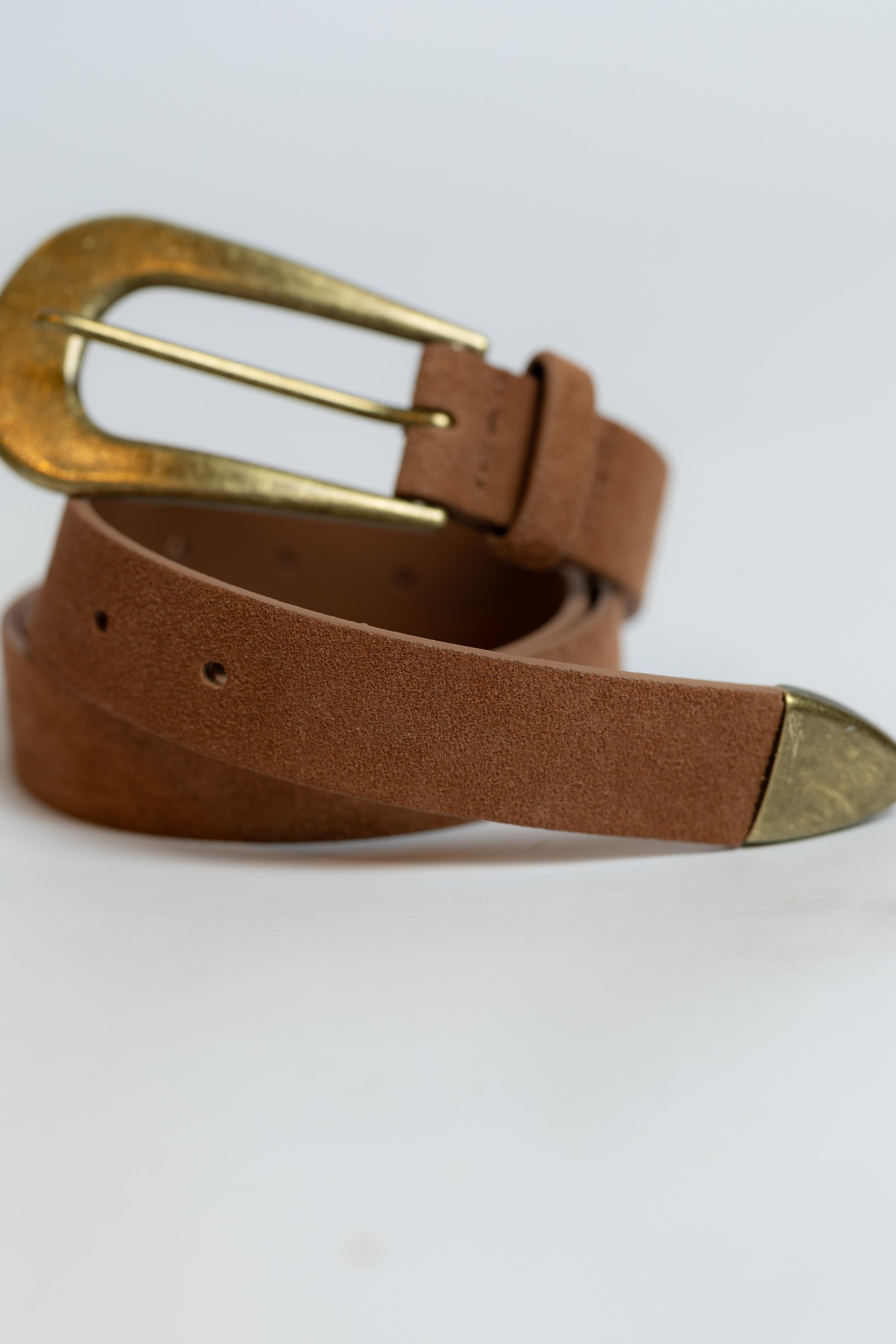 Brown leather belt with a gold buckle on a light gray background