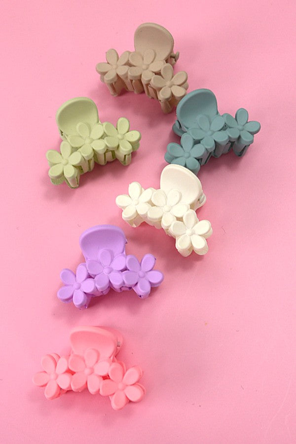 Set of six matte flower hair claw clips in pastel colors displayed on a pink background.
