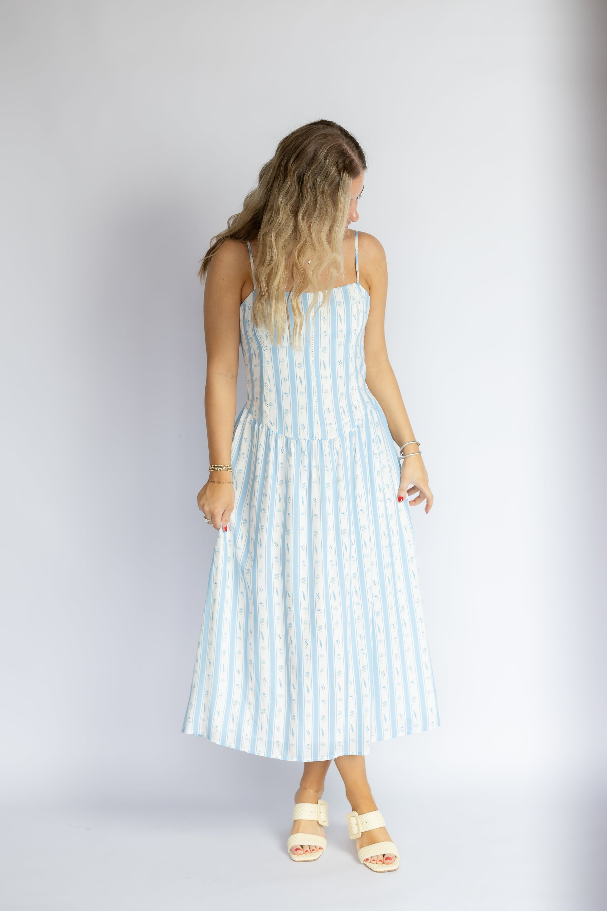 Woman wearing a light blue and white striped dress against a plain background