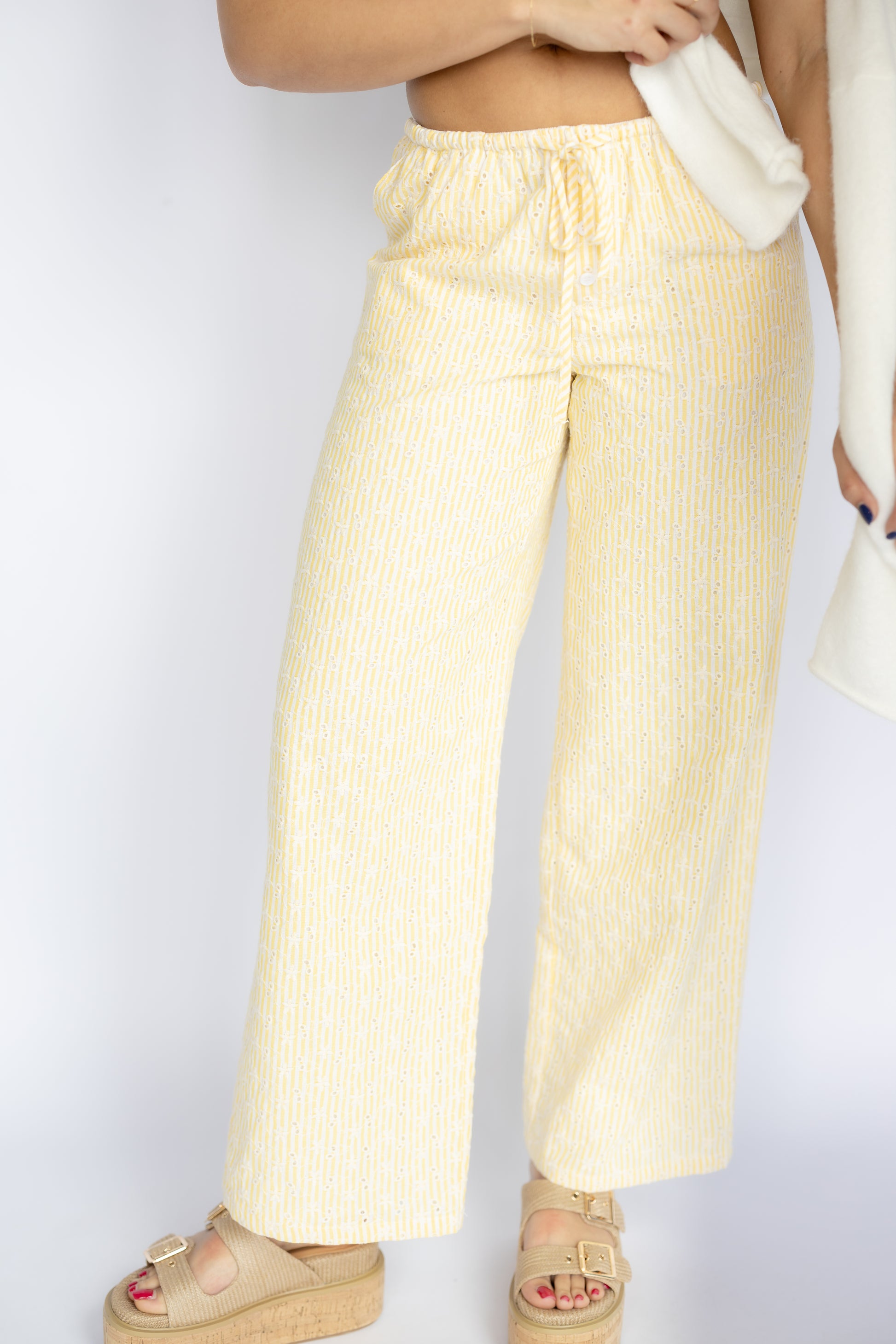 Person wearing light yellow striped pants on a plain background