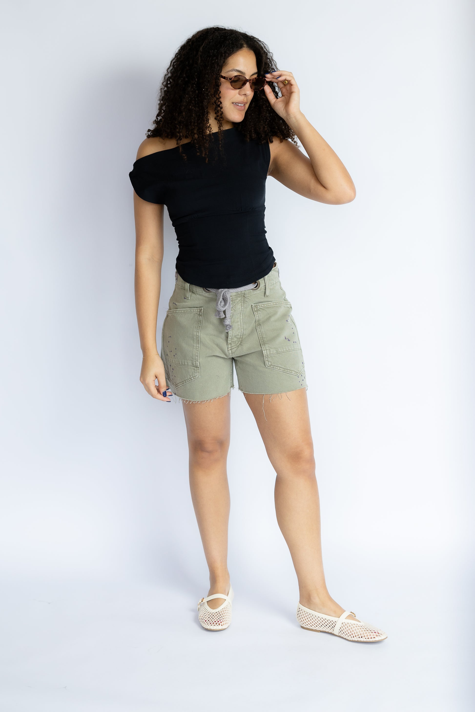 Woman wearing a black top and green shorts on a white background
