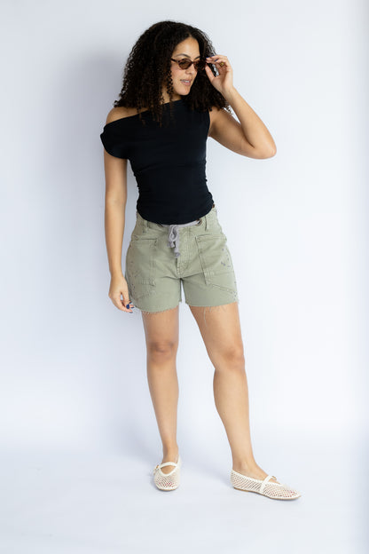 Woman wearing a black top and green shorts on a white background