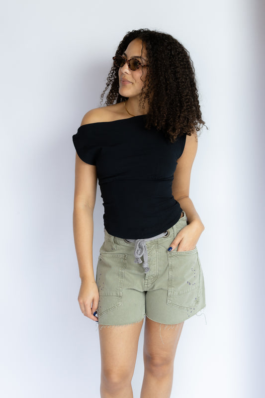 Woman wearing a black top and green shorts against a white background