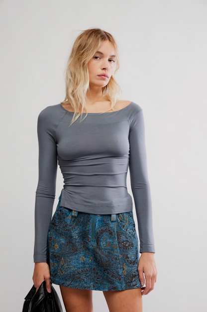 Woman wearing slate gray fitted wide-neck long sleeve top with blue jacquard mini skirt