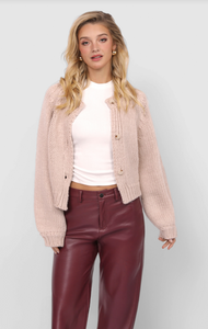 Model wearing blush chunky knit cropped button cardigan styled with white tee and burgundy leather pants