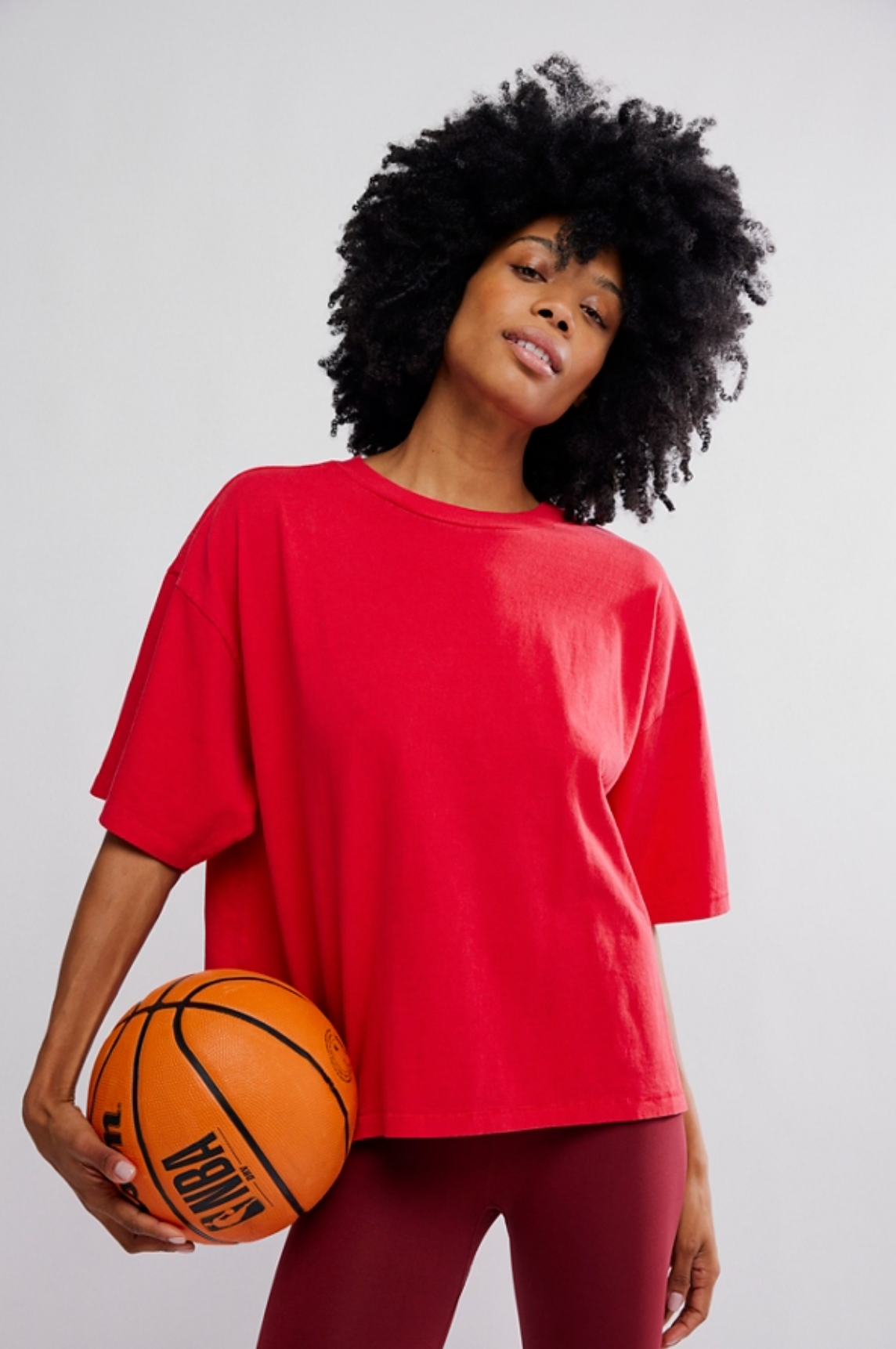 woman wearing red oversized cotton t-shirt holding a basketball