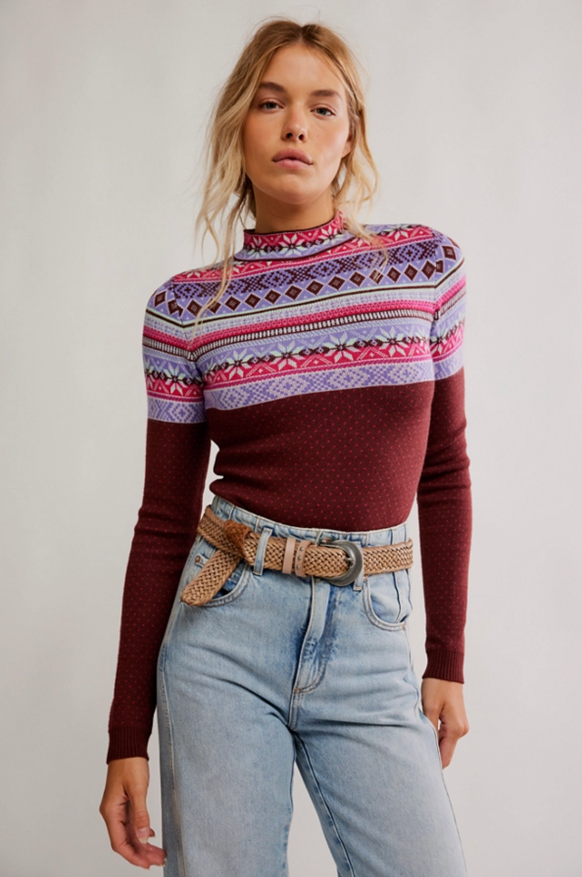 Woman wearing a retro Fair Isle print mock neck long sleeve bodysuit tucked into light wash denim jeans.