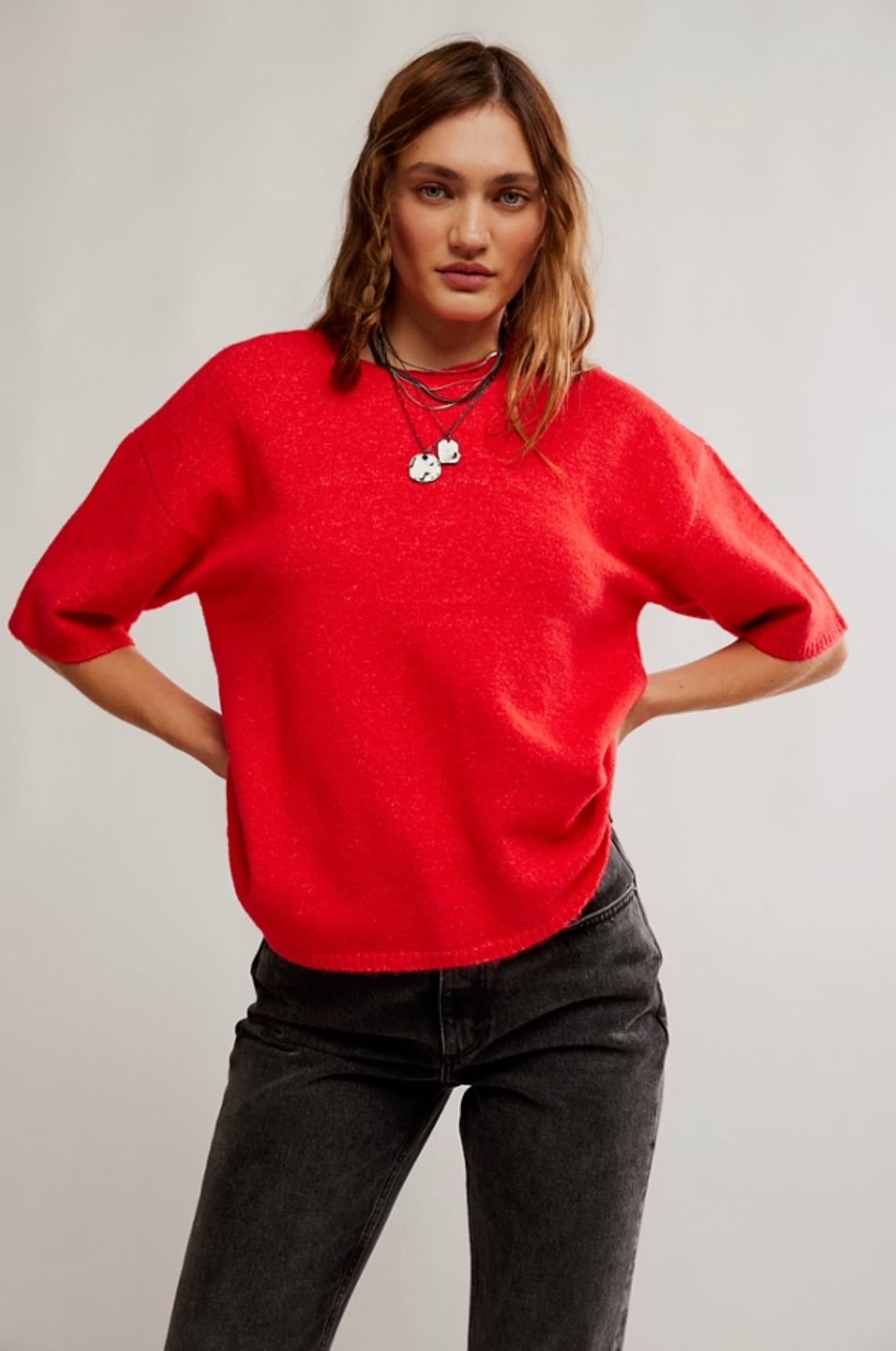 Person wearing a red sweater and black pants against a plain background