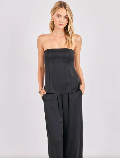 Woman wearing a black satin tube top with matching wide-leg pants.