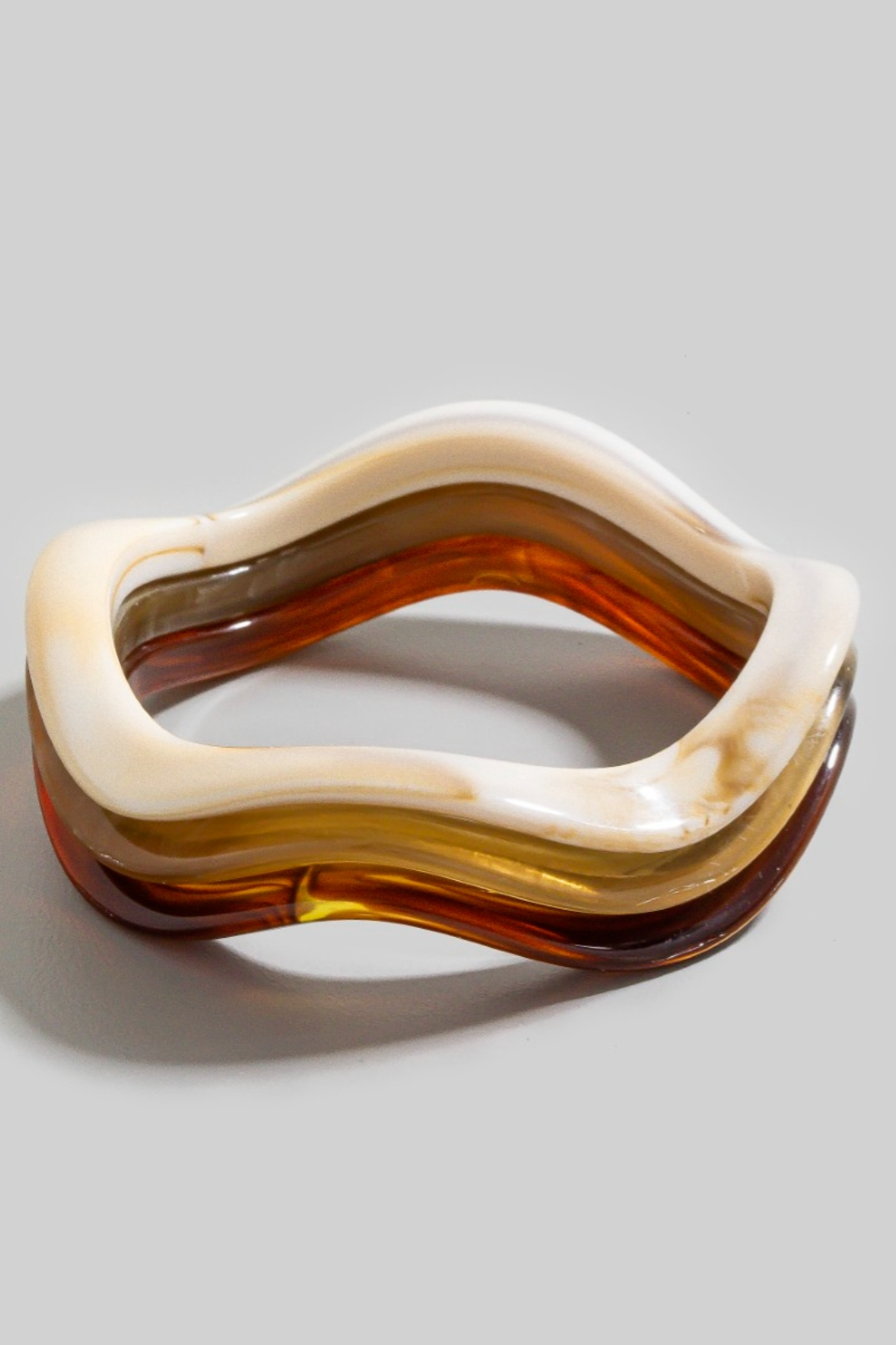 Three-piece wavy resin bracelet set in ivory, honey, and amber stacked together