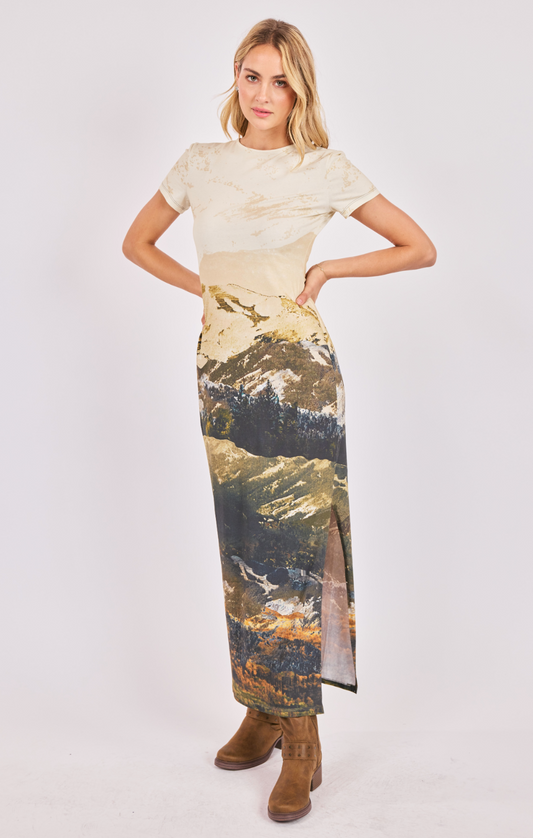 Woman wearing a dress with a patterned skirt and plain top on a white background