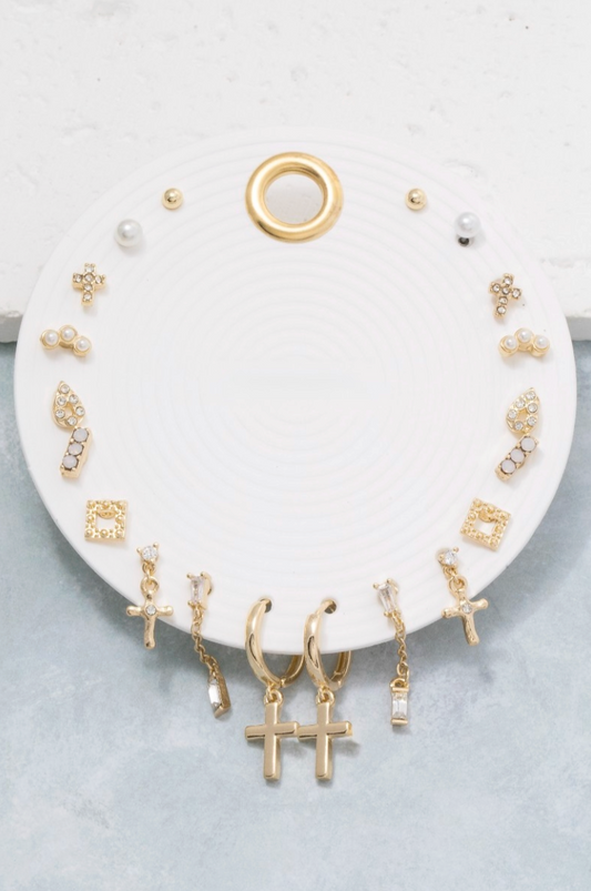 Collection of gold earrings on a white circular stand with a gray background