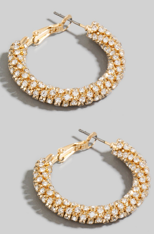 Gold hoop earrings with clear gemstones on a gray background