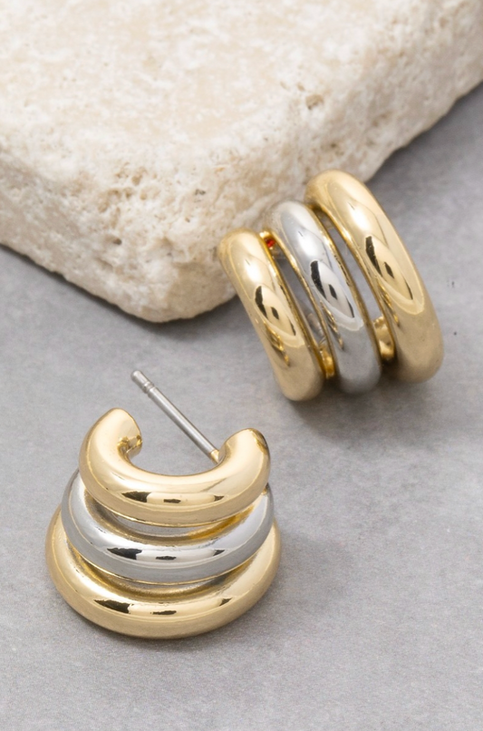 Gold and silver hoop earrings on a stone surface