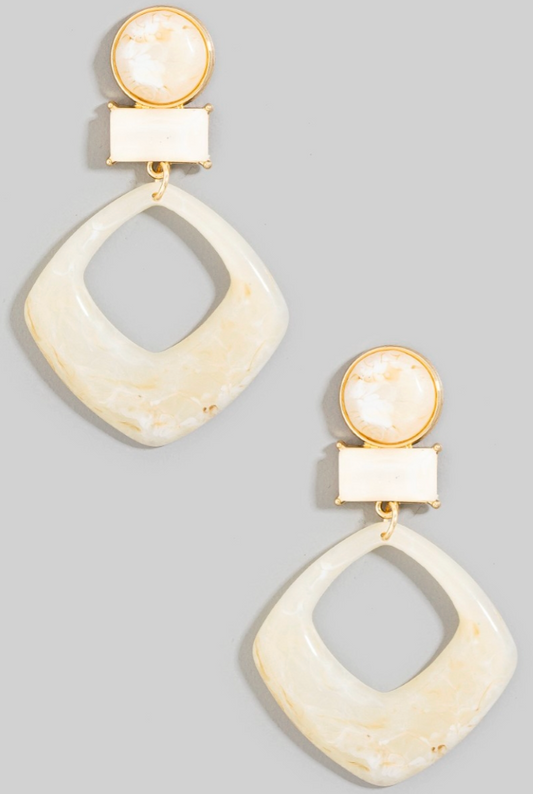 Pair of gold and cream-colored earrings on a gray background