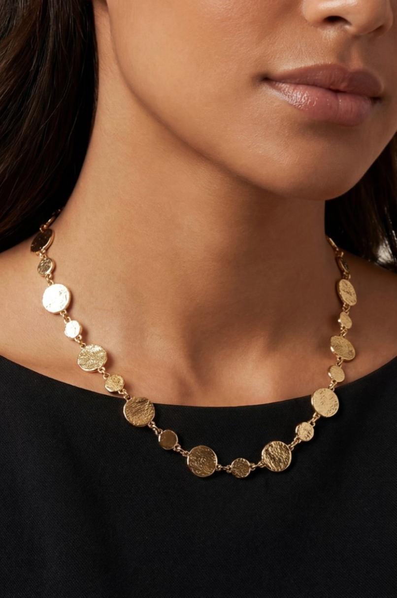 Gold necklace worn by a person against a black background