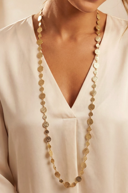 Long beaded necklace worn by a person in a white shirt