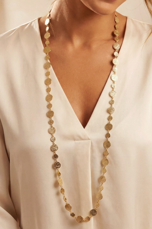 Long beaded necklace worn by a person in a white shirt