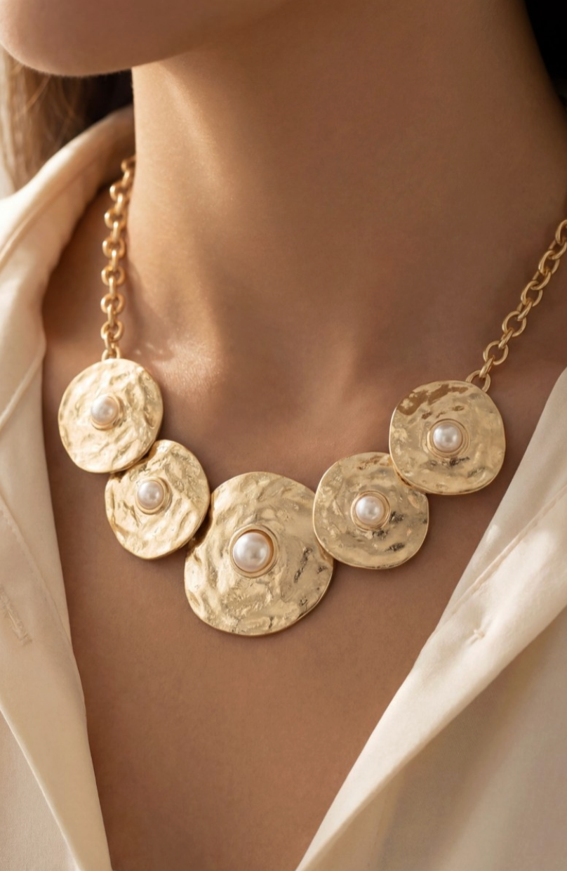 Gold necklace with circular pendants and pearls worn by a person