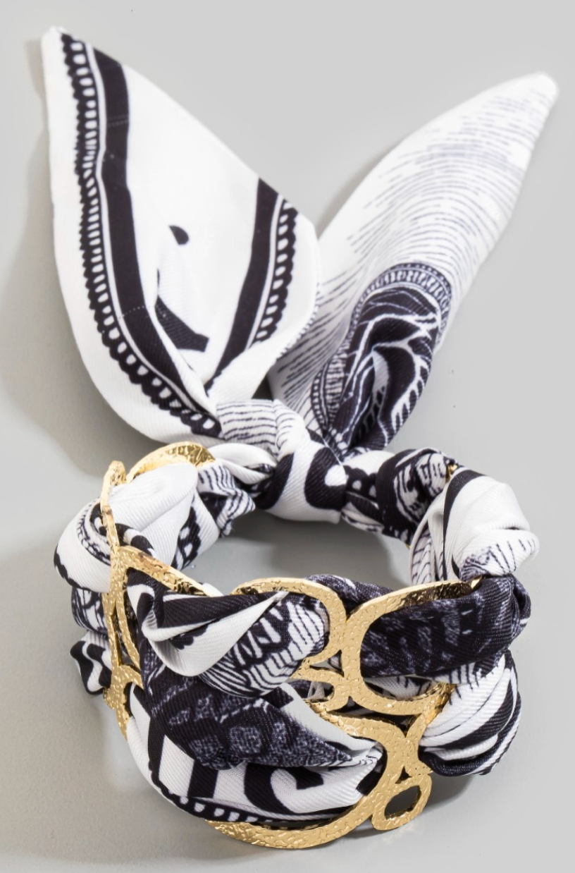 Black and white patterned bandana bracelet with gold accents on a light gray background