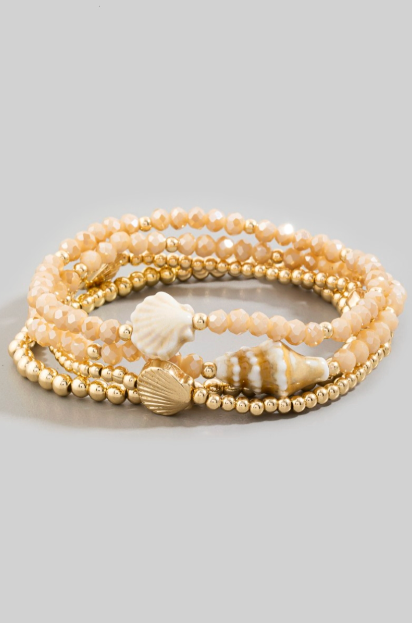 Set of pearl and gold beaded bracelets with shell accents on a light gray background