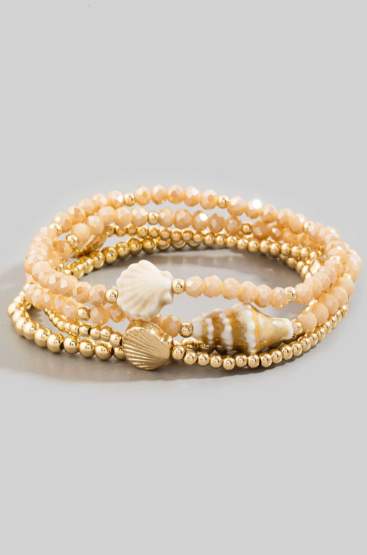 Set of pearl and gold beaded bracelets with shell accents on a light gray background