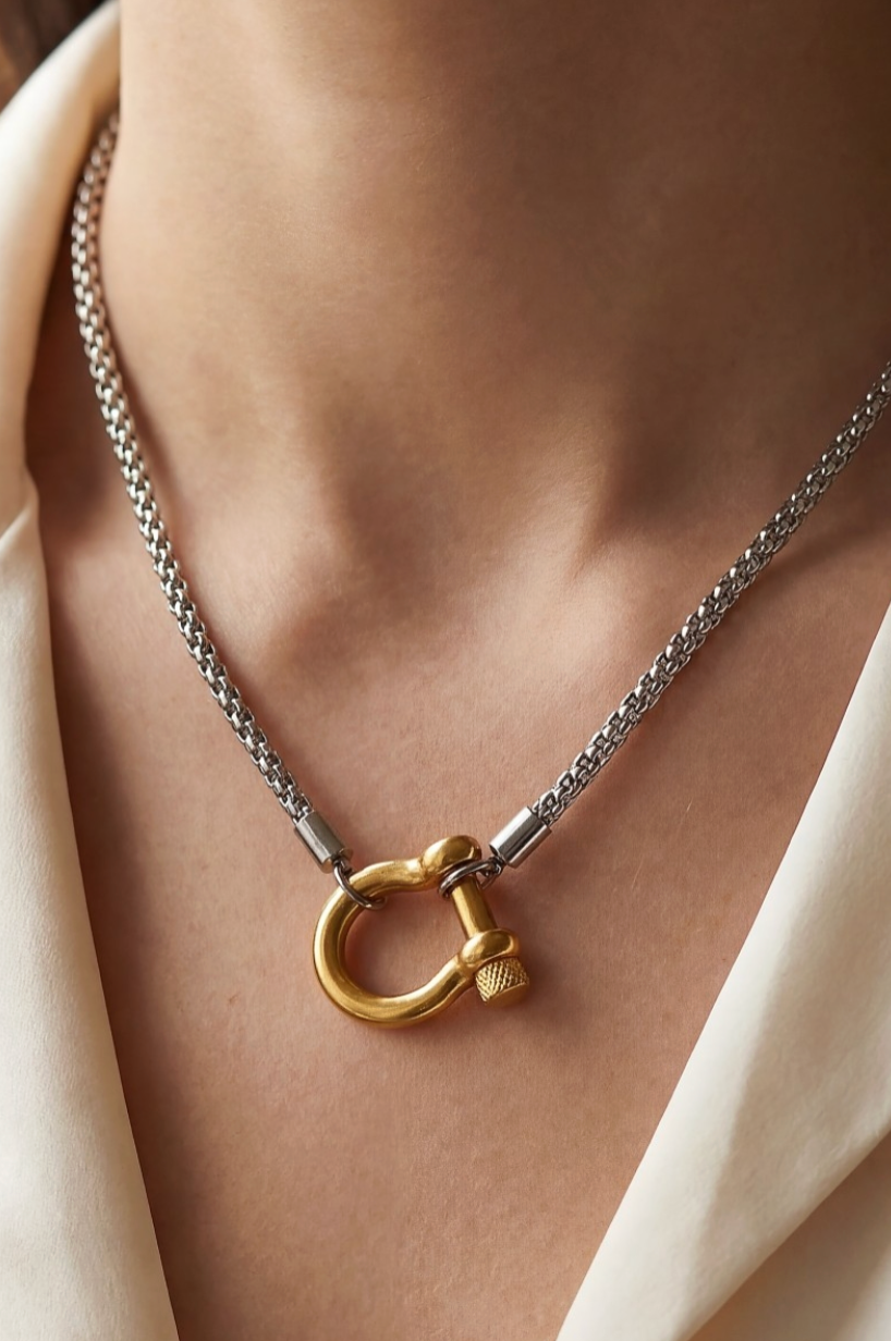 Necklace with a gold clasp on a person wearing a beige garment