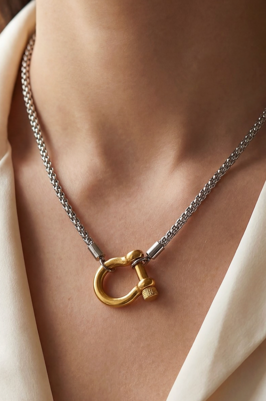 Necklace with a gold clasp on a person wearing a beige garment