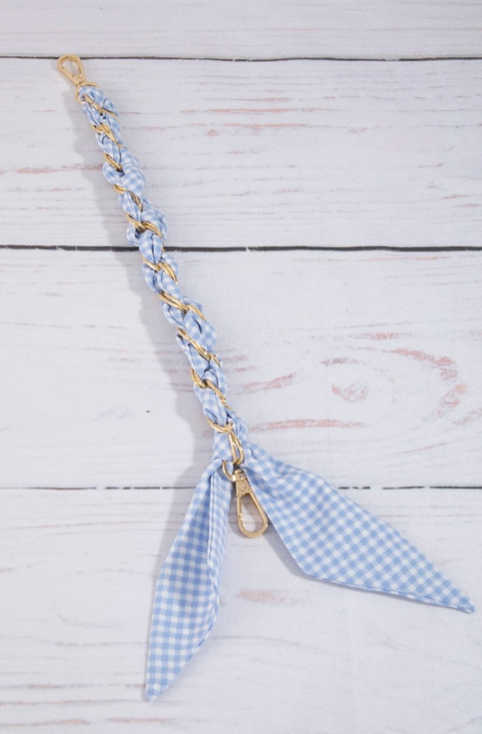 Blue gingham keychain with gold clasp on a light wooden surface