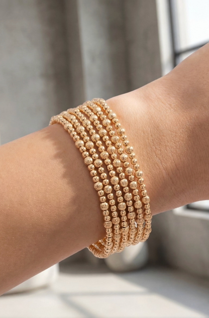 Gold beaded bracelet on a wrist with a neutral background