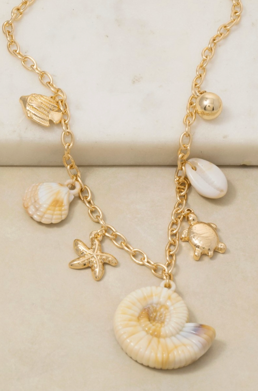 Gold necklace with shell and turtle charms on a beige background